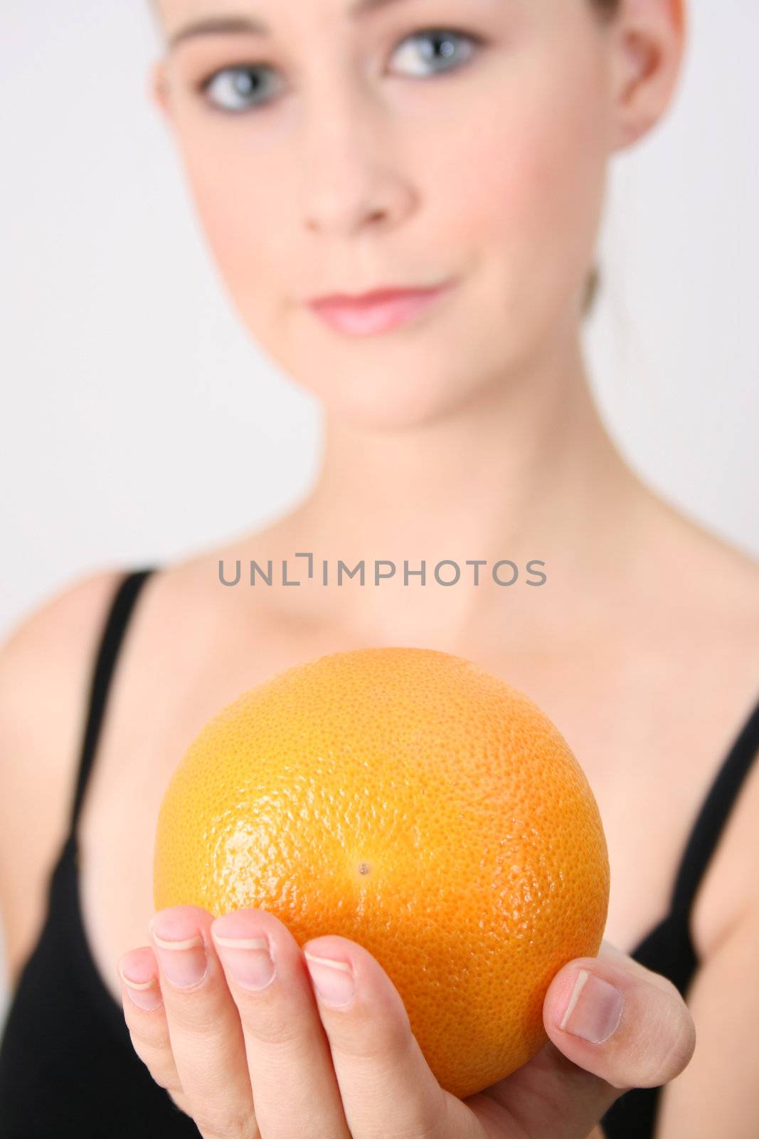 Gym girl holding orange.  FOCUS ON ORANGE