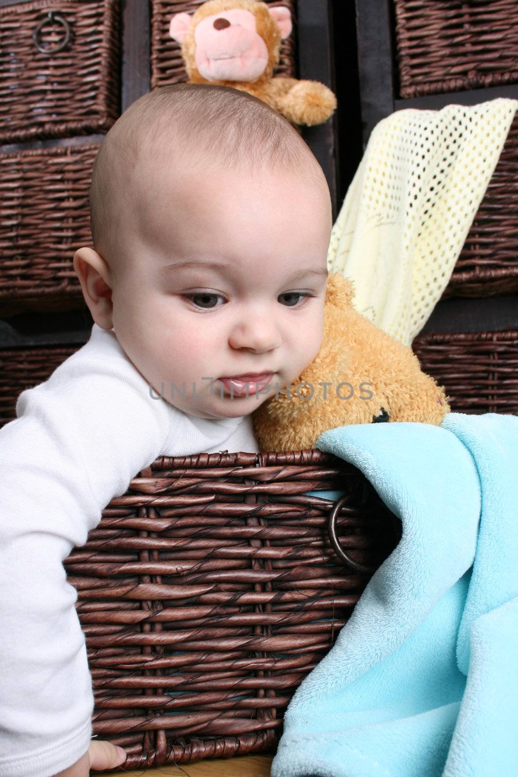 Six month old baby sitting infront of wooden drawers