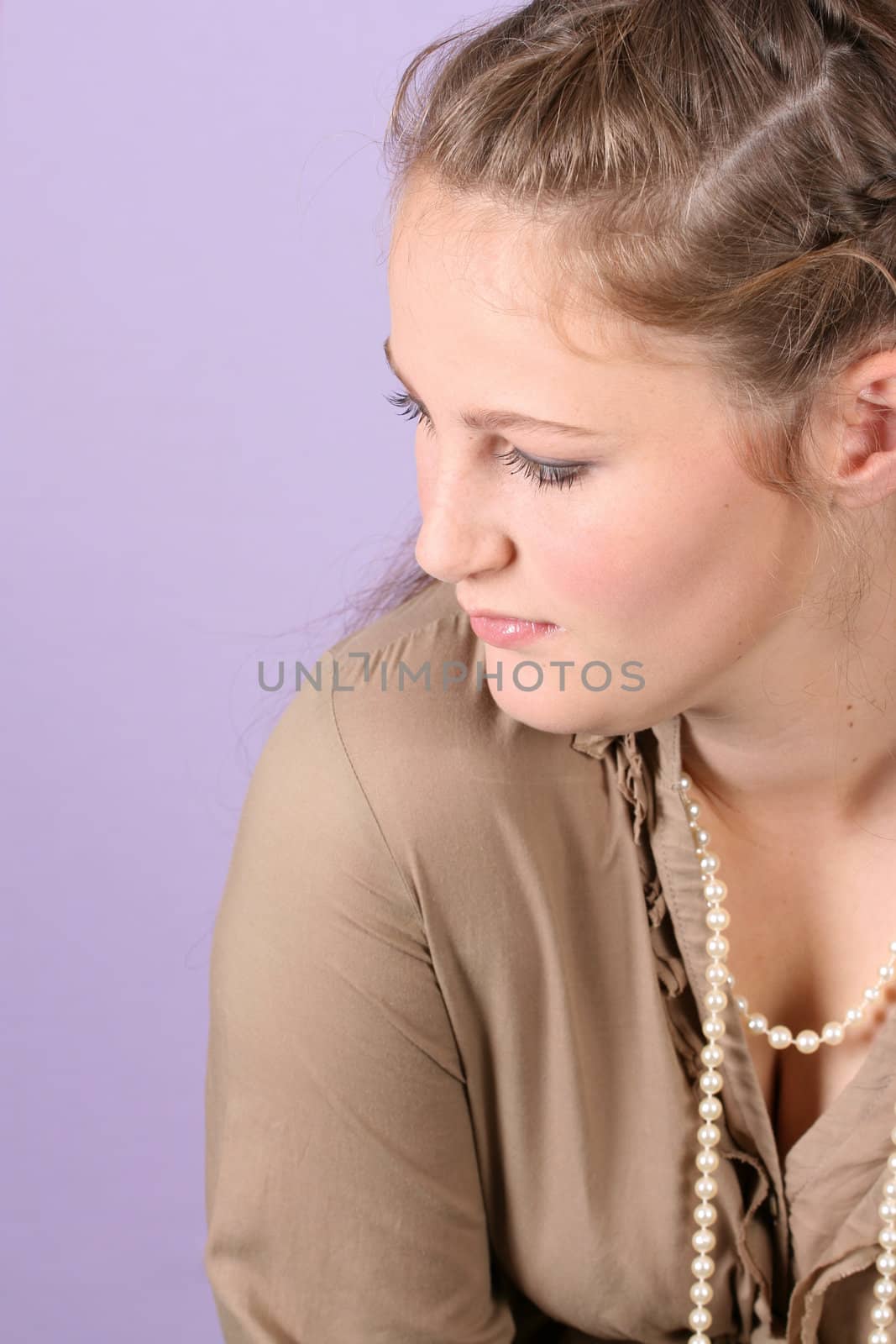Beautiful teenage female against purple background, wearing pearls