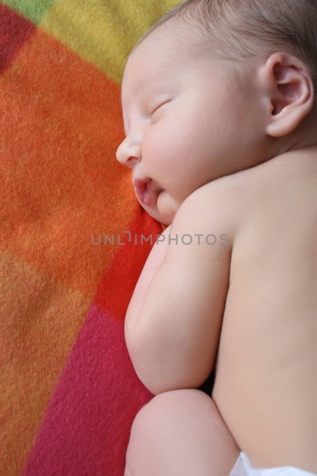 Newborn baby sleeping on a colorful soft blanket