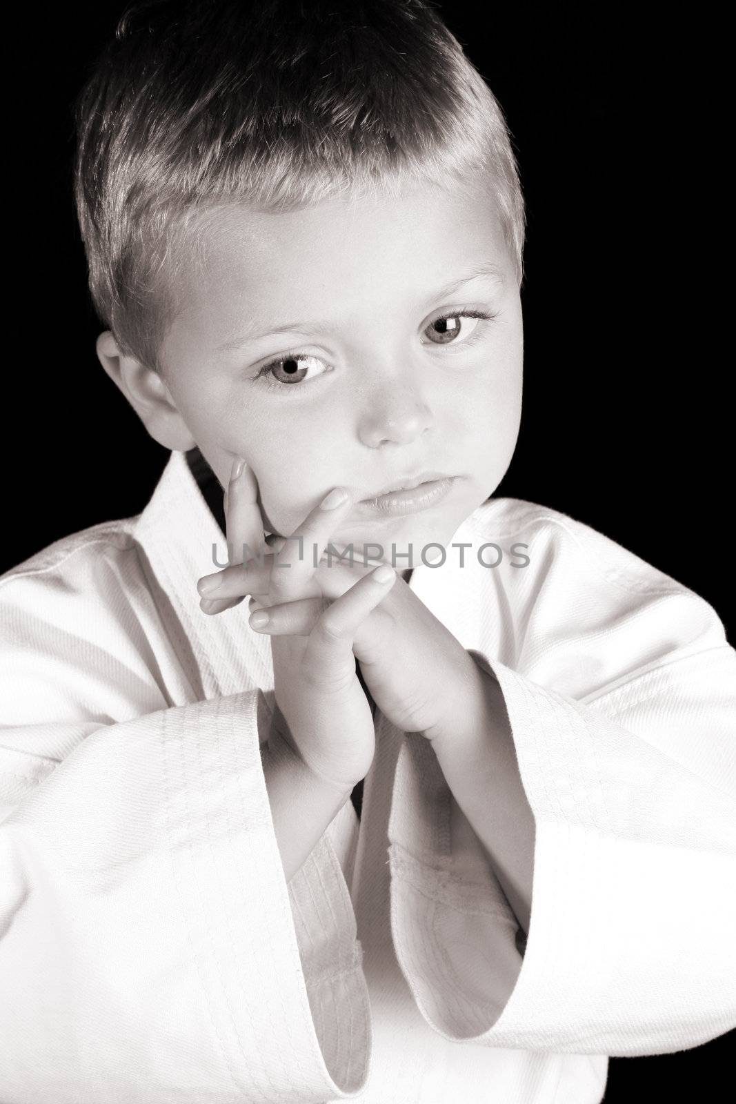 Young boy wearing his karate uniform on a black background
