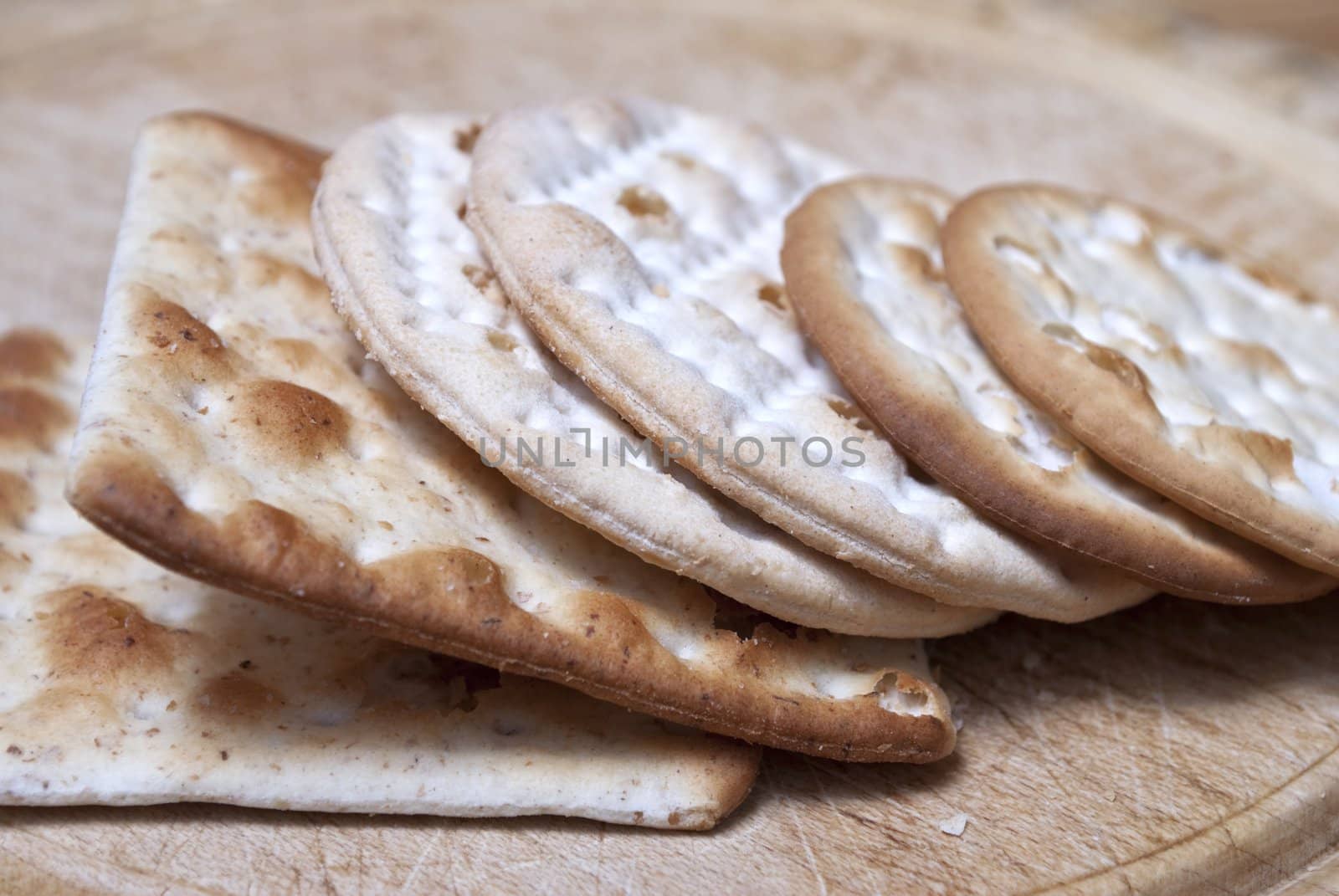 Closeup of crackers leaning against eachother on an old wooden chopping board.  Cut-marks visible.