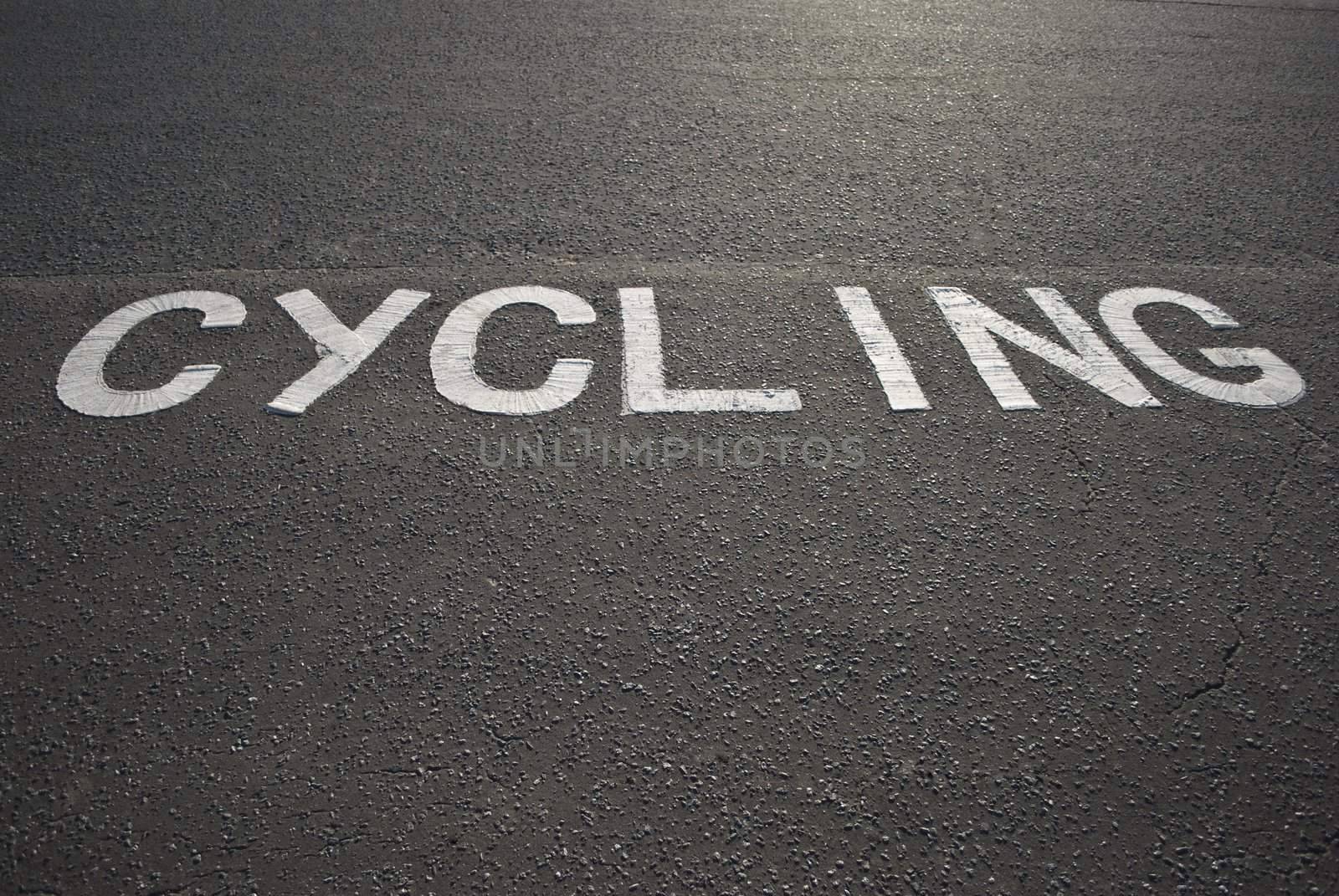 The word 'Cycling' painted in white on tarmac in winter sunlight.