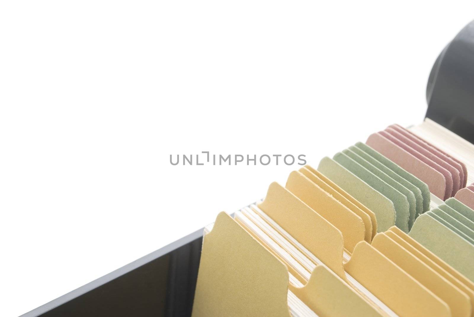Closeup of an opened box of index cards, isolated on a white background, with copy space above and left.  Black box, white cards with dividers coloured pink, green and yellow.