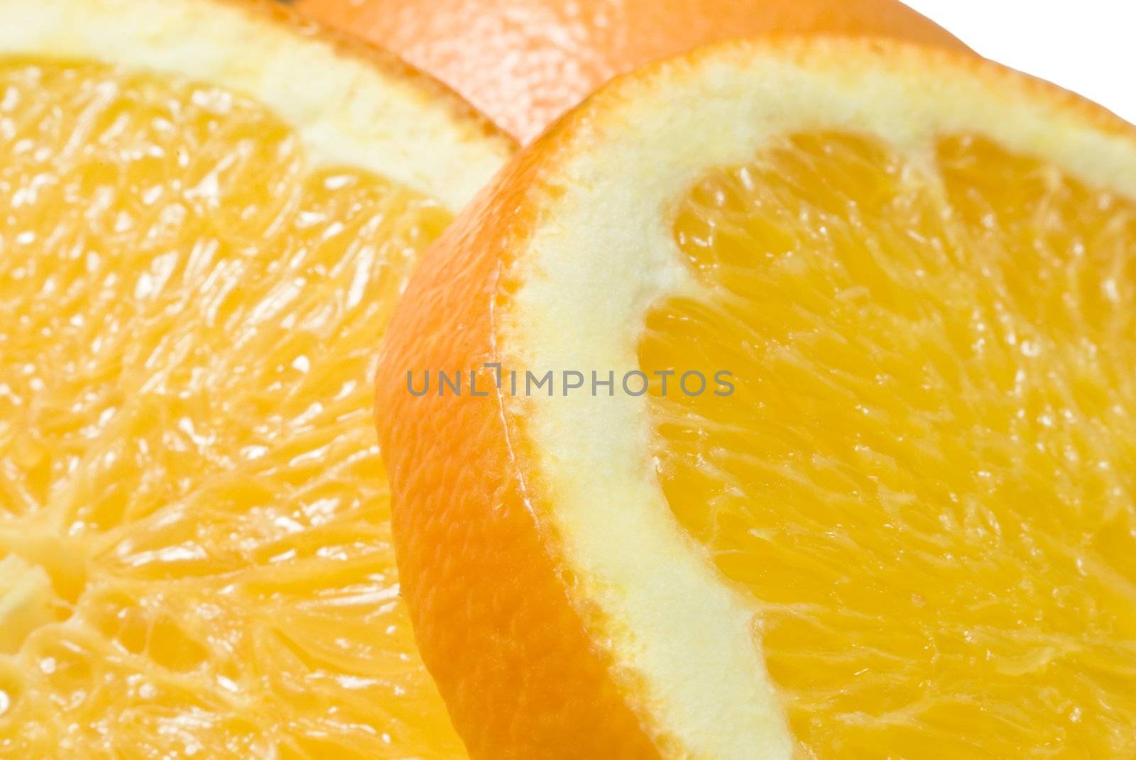 Close up (macro) of two slices of orange (foreground) and an upturned half-orange (middle-ground) with white background.
