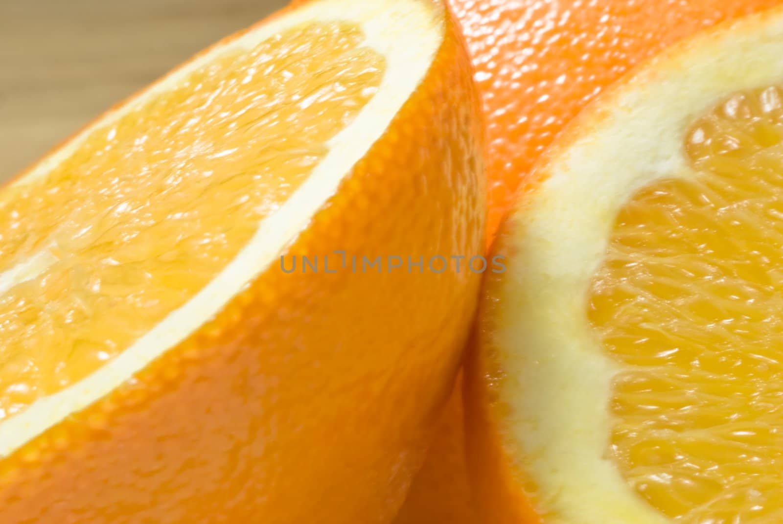 Three parts of an orange in close up (macro), on beech wood table.  