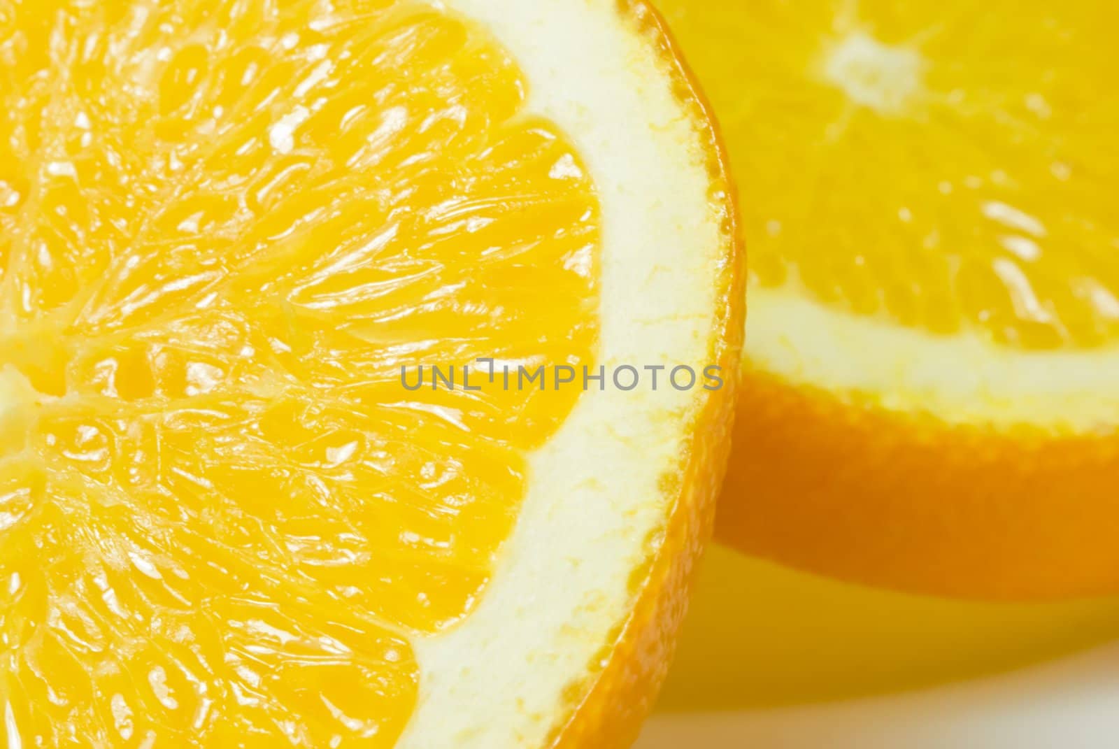 Two orange slices on a white china plate, shot in close up (macro).  Shadows visible.