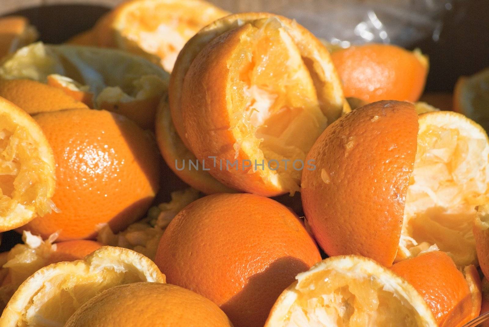 Closeup of squeezed out orange halves, discarded after juicing.  Shot outdoors in strong sunshine.