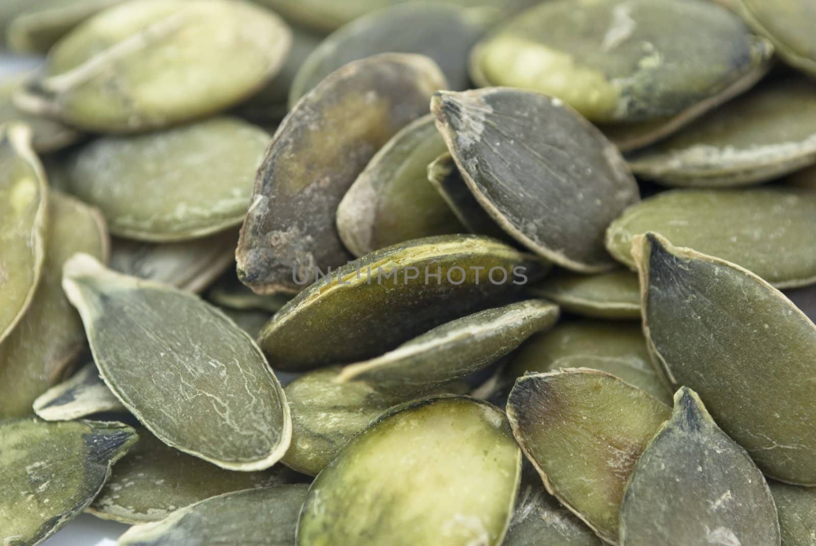 Close-up shot of numerous organic pumpkin seeds in their raw state.