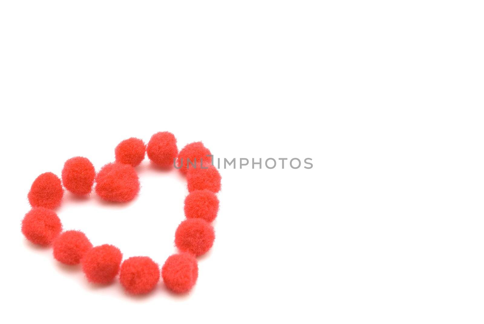 A heart shape made up from assembled red fluffy pompom balls. 
White background