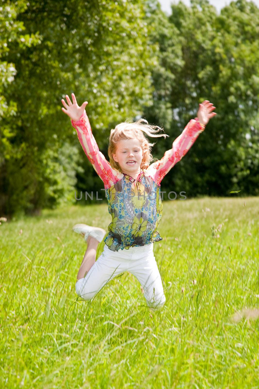 Child of 5 years old jumping high in the field arms outstretched