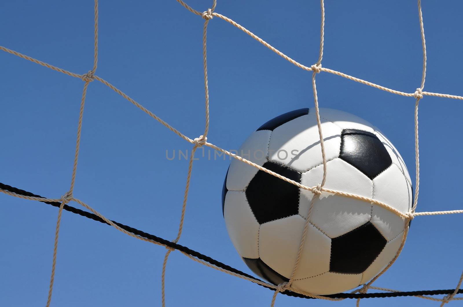 Closeup of soccer ball in net with copy space.