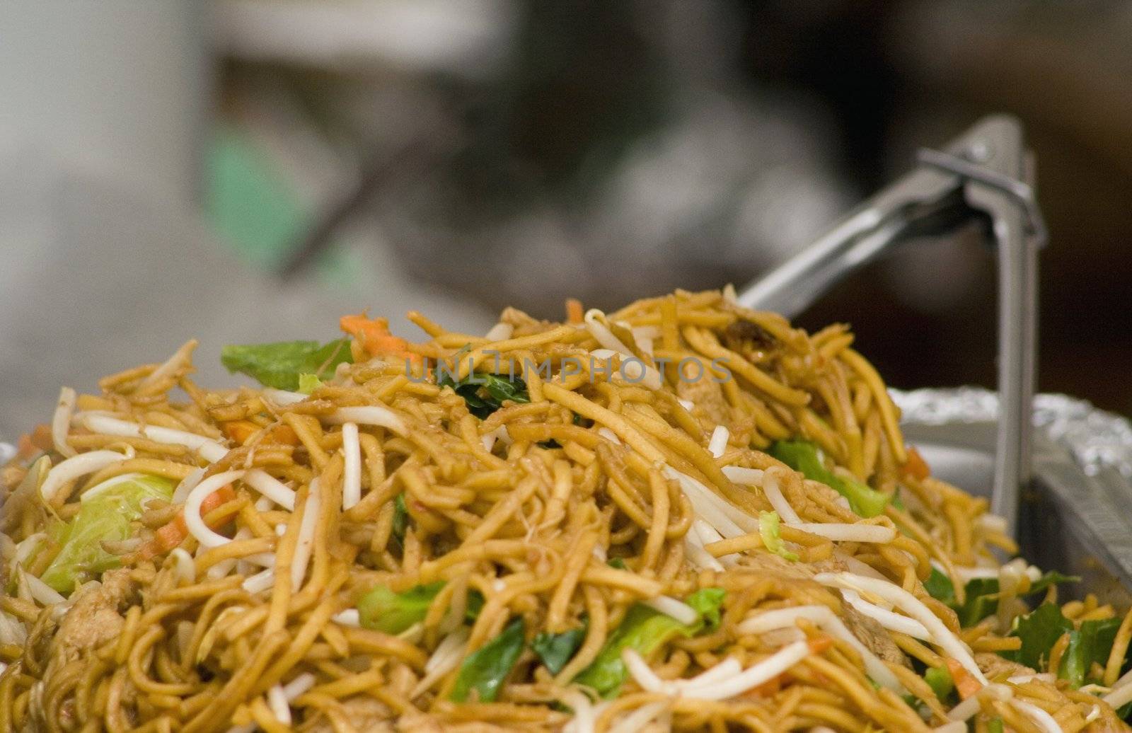 stir-fry vegetables with noodles with a pair of tongs in the background