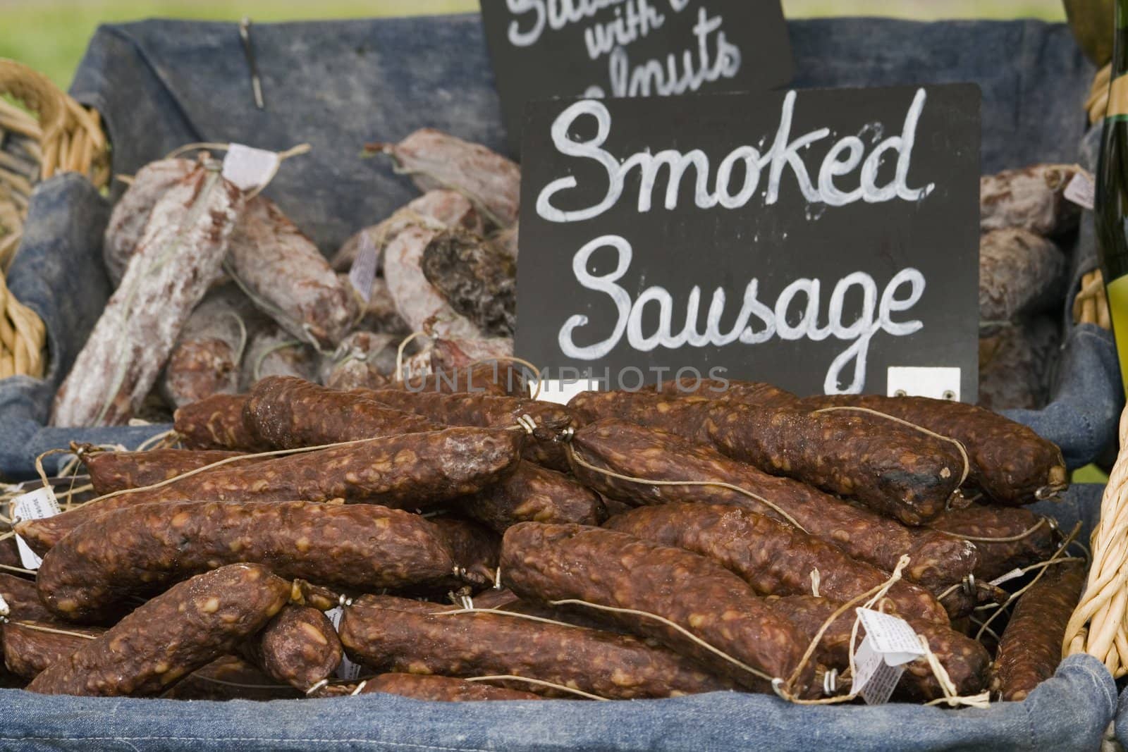 a basket of smoked sausages for sale on a market stall