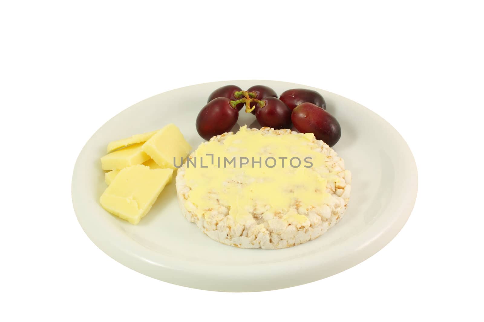 a plate with chesse, grapes and a rice cake on it