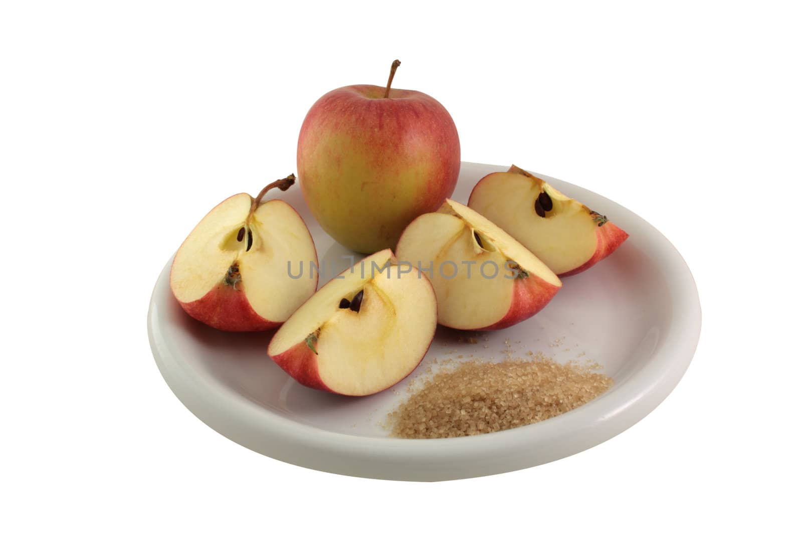 A plate with sugar and two apples on it, one cut and the other whole