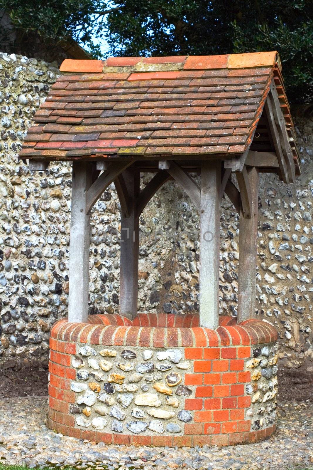 A old wishing well with a brick wall behind it