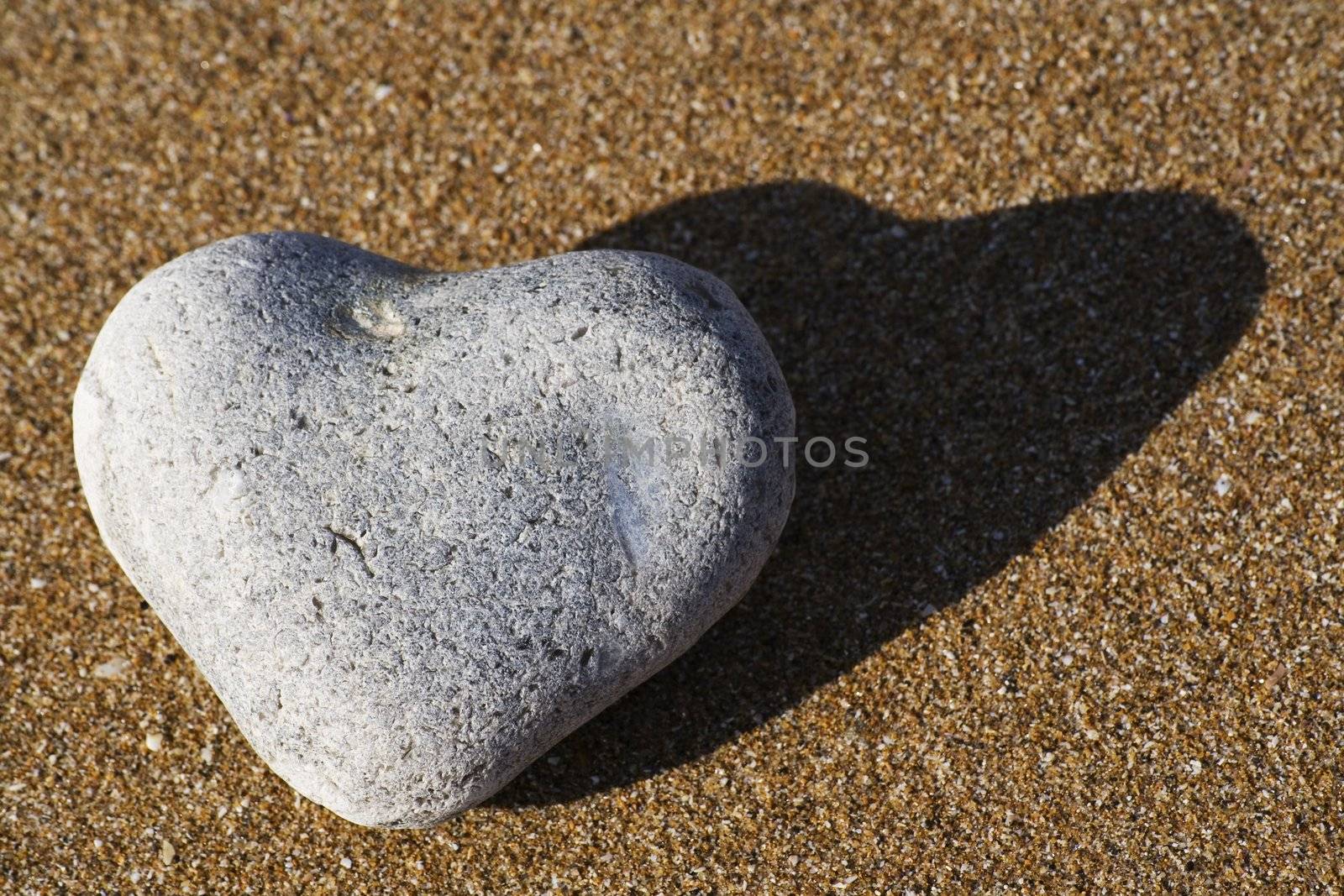 A heart shaped stone on a sandy beach, close-up