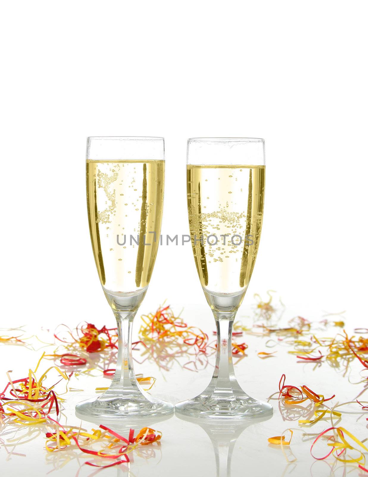 Pair of champagne flutes ready for celebrate. Confetti and white background