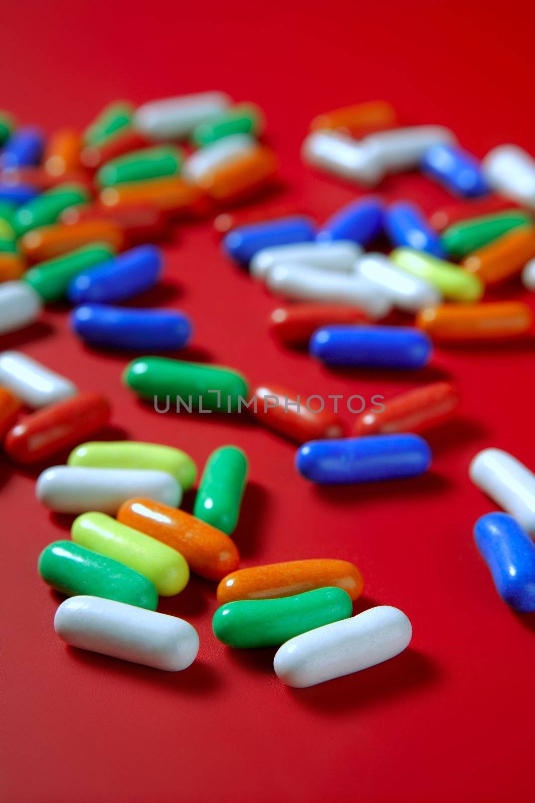 Colorful candy spread over red background, selective focus