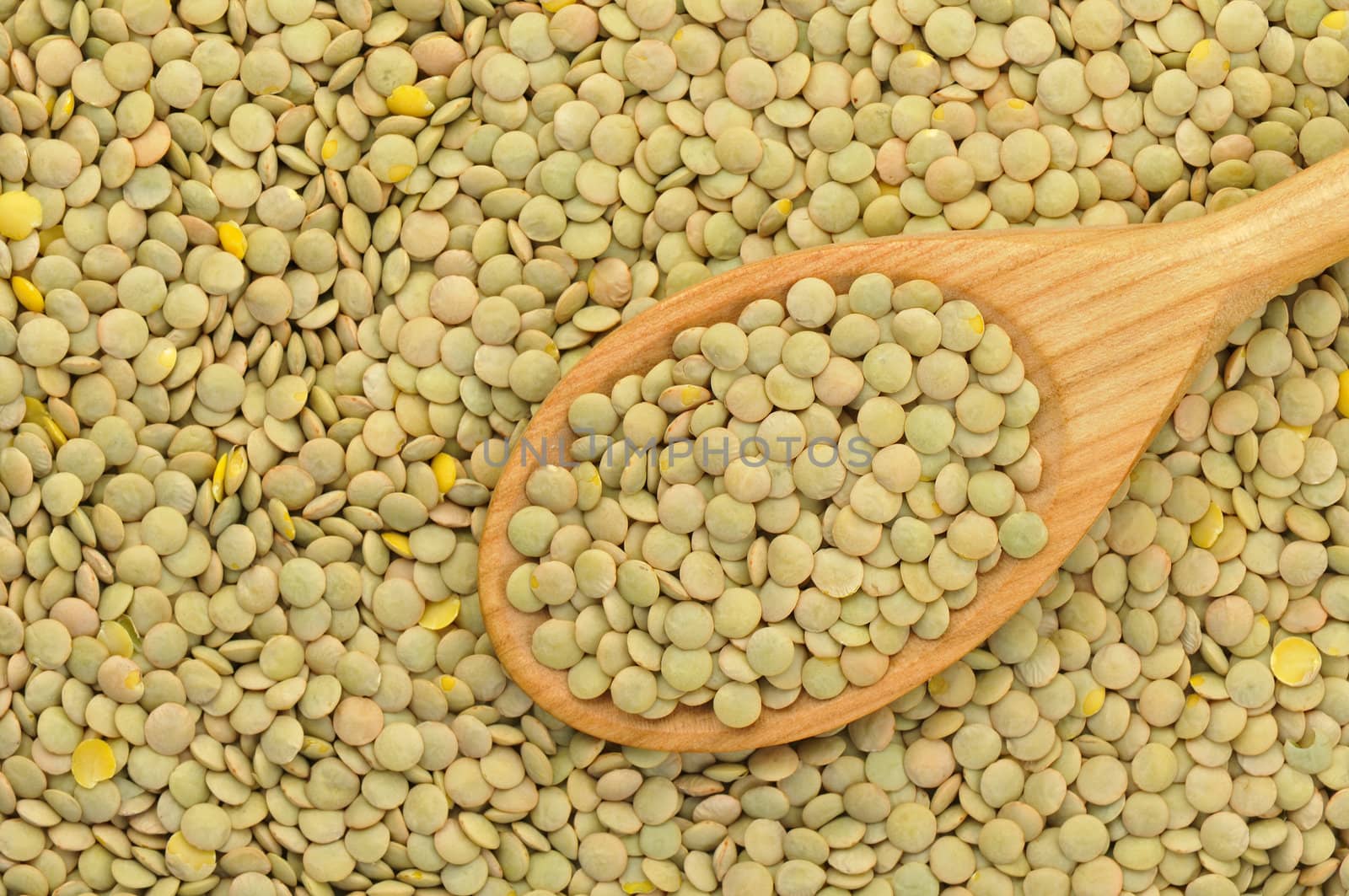 Top view of green lentils in a wooden spoon
