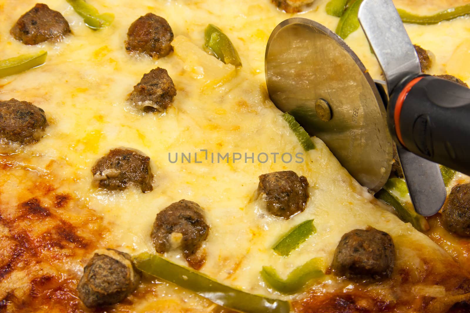 Picture of Closeup of meatball pizza with pizza wheel
