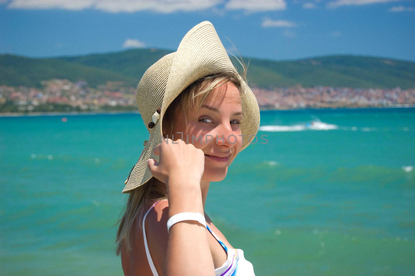 Lovely woman in hat over seashore background