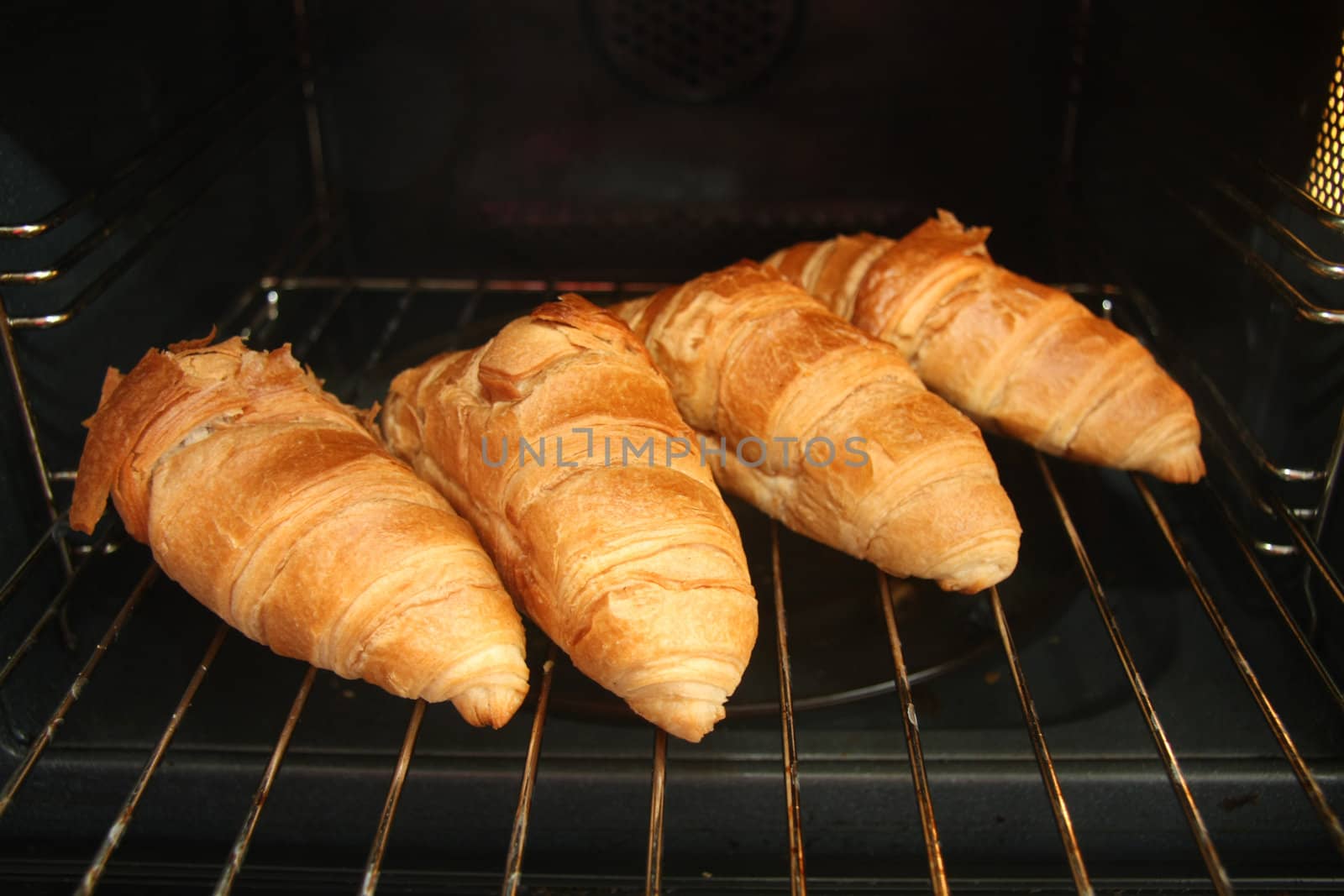 Four fresh backed French croissants in the oven
