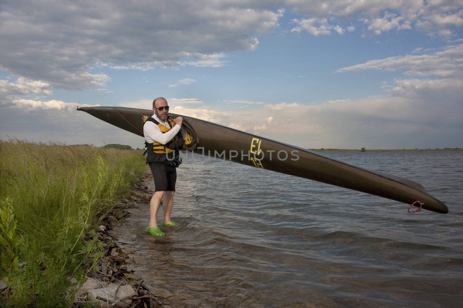 mature paddler and racing kayak by PixelsAway