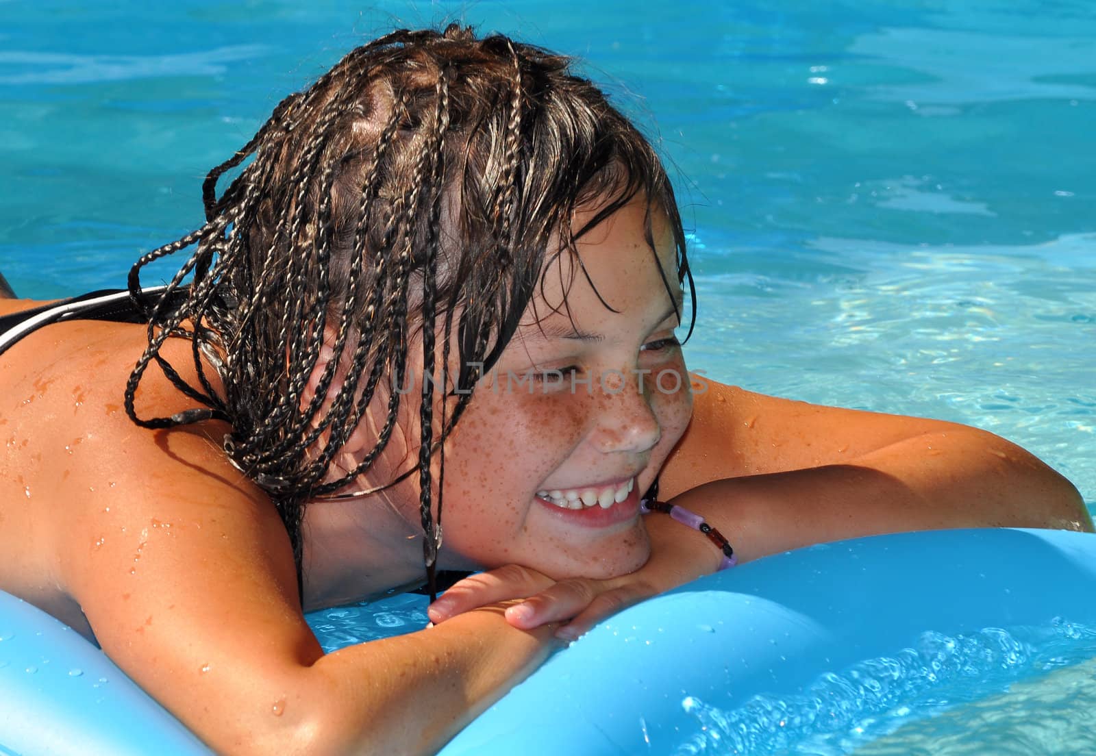 A young girl lying on an air mattress in a garden pool.