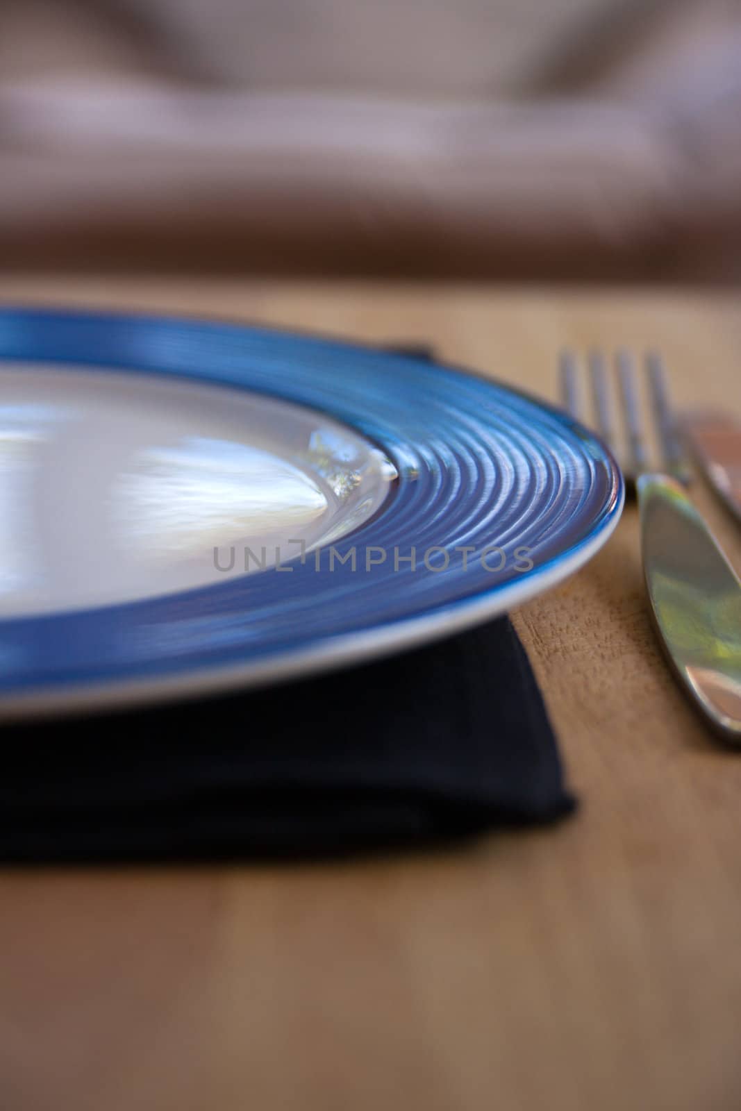 Blue and white plate with fork and black napkin on a wooden table