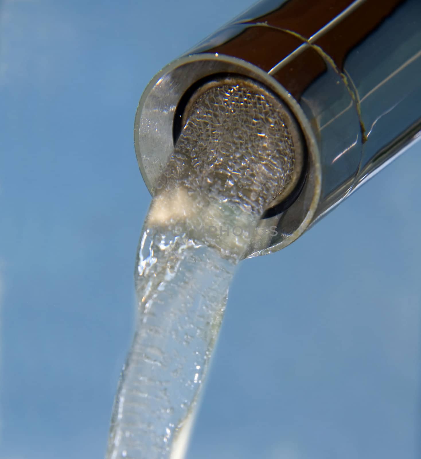 bubbling, flowing water from the tap isolated on blue