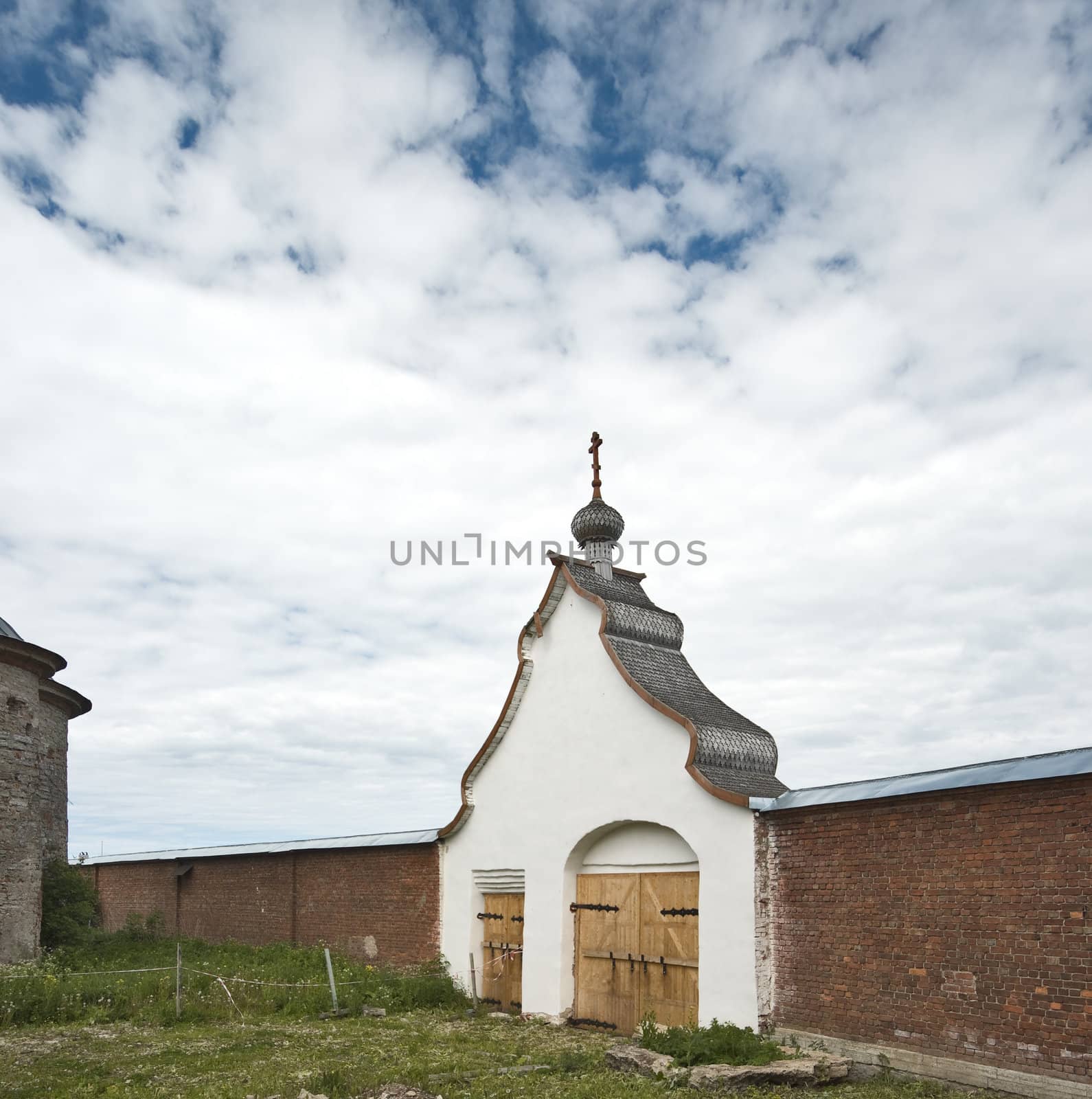 Old enter gates to monastery with onion dome and cross on the top