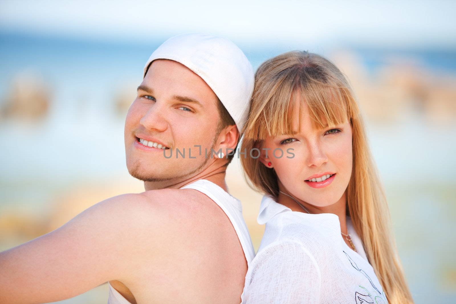 Happy couple sitting on the beach near the ocean