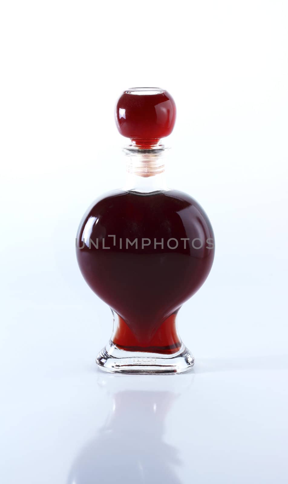 Bottle of red liqueur on shiny background