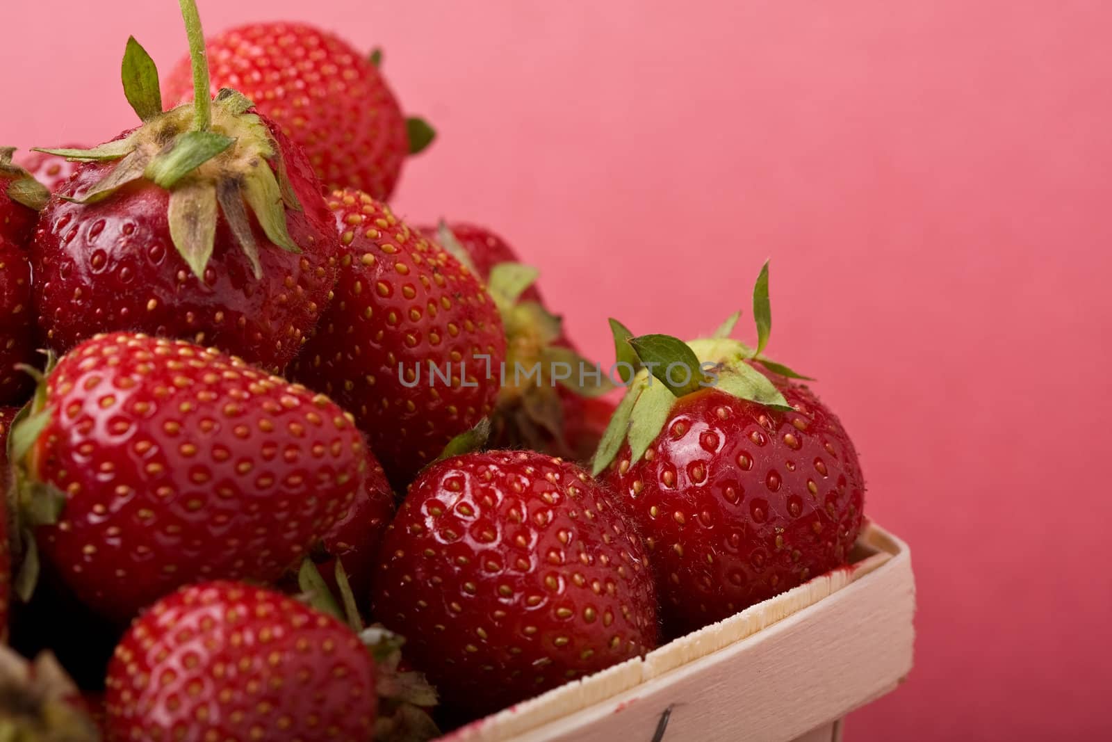 wooden quart of ripe strawberries on a solid background