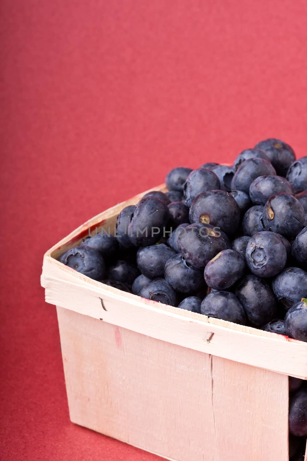 wooden quart of blueberries on a red background