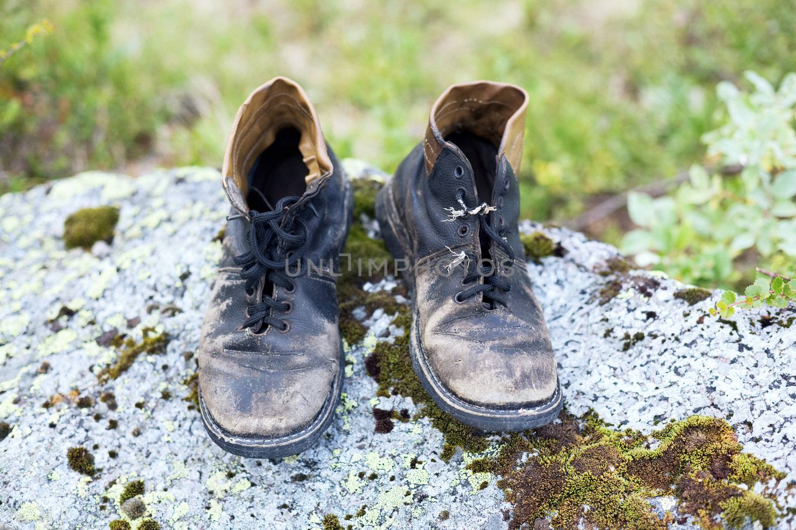 Old leather brown dirty boots in wood on a stone