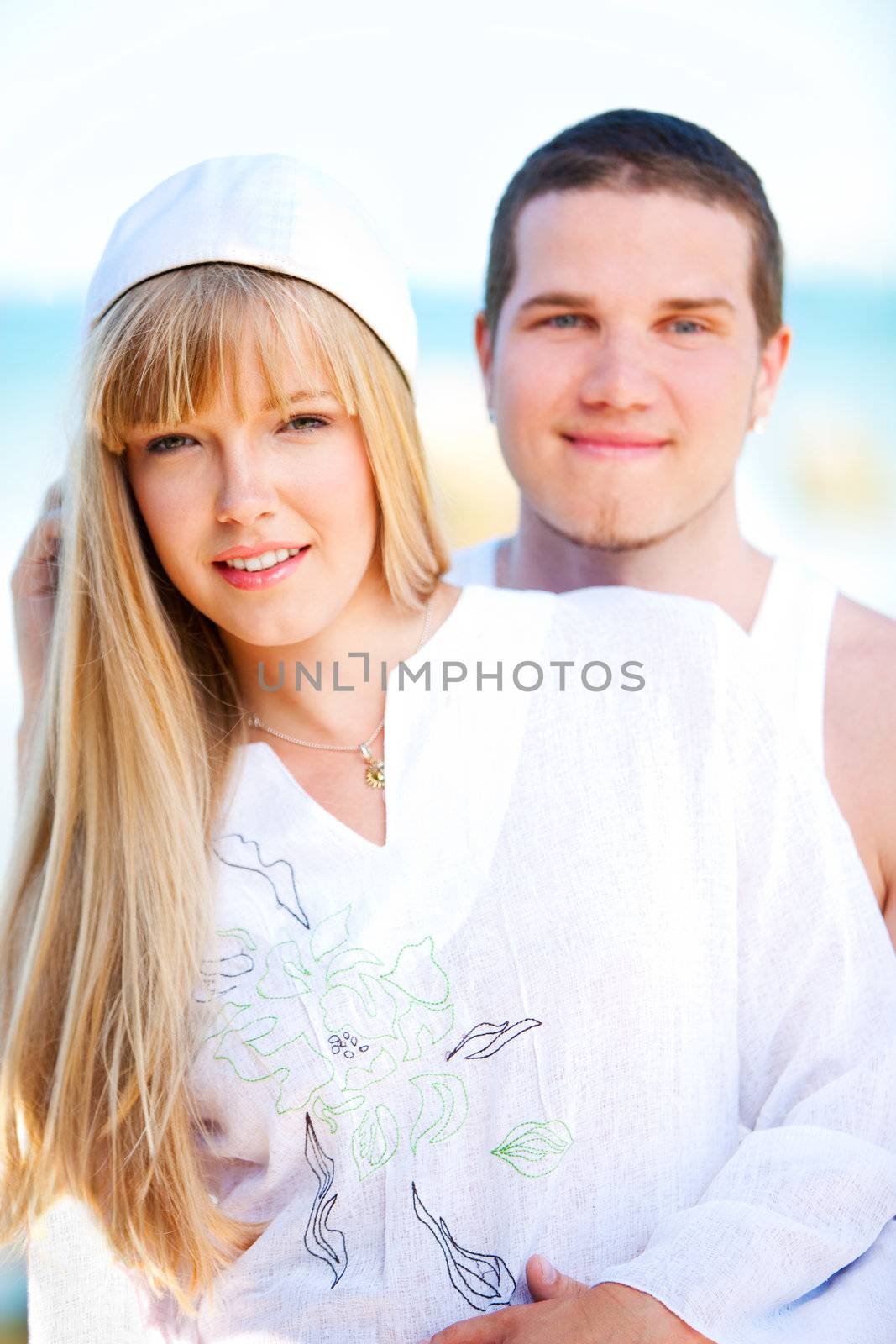 Happy couple standing on the beach near the ocean