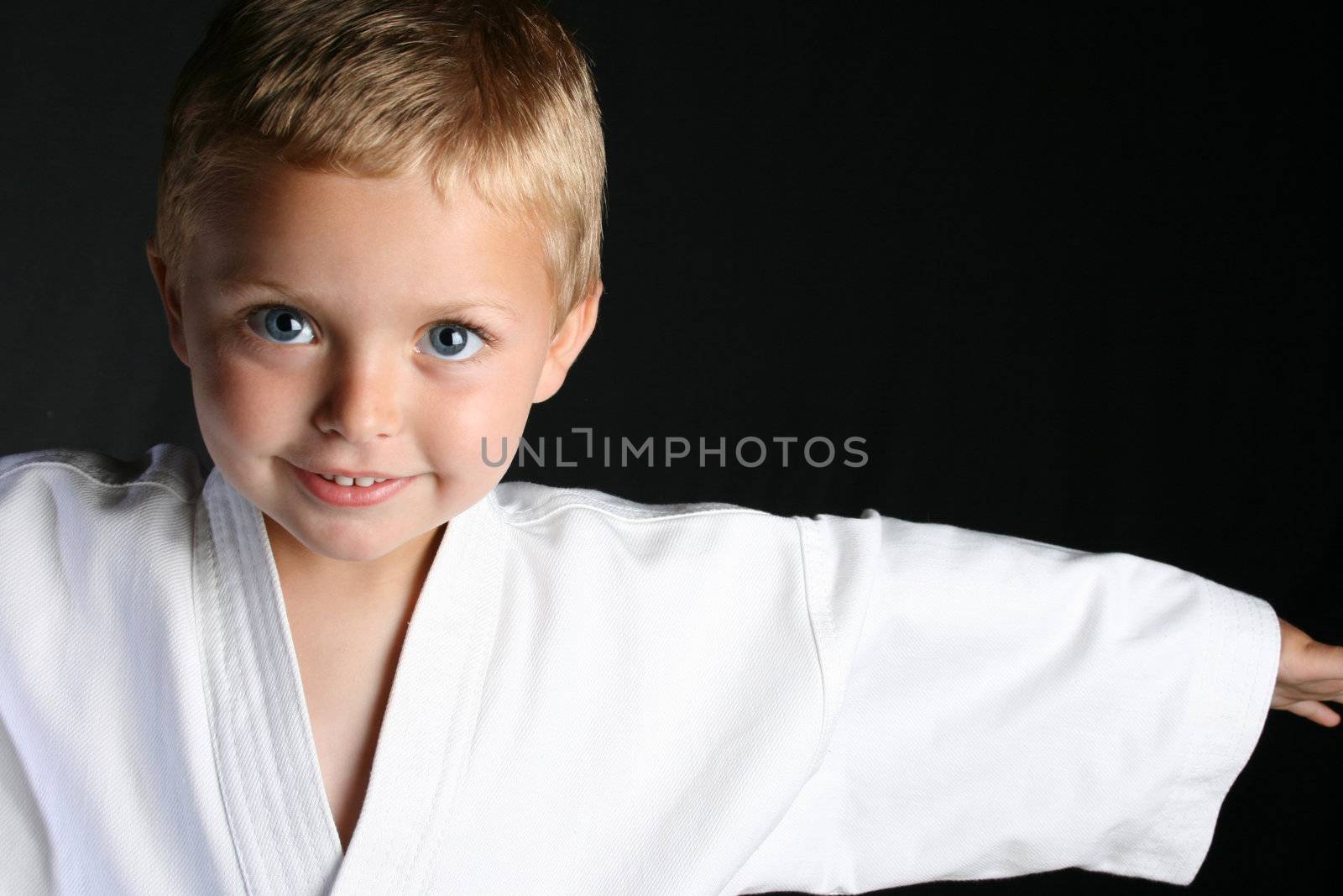 Young boy wearing his karate uniform on a black background
