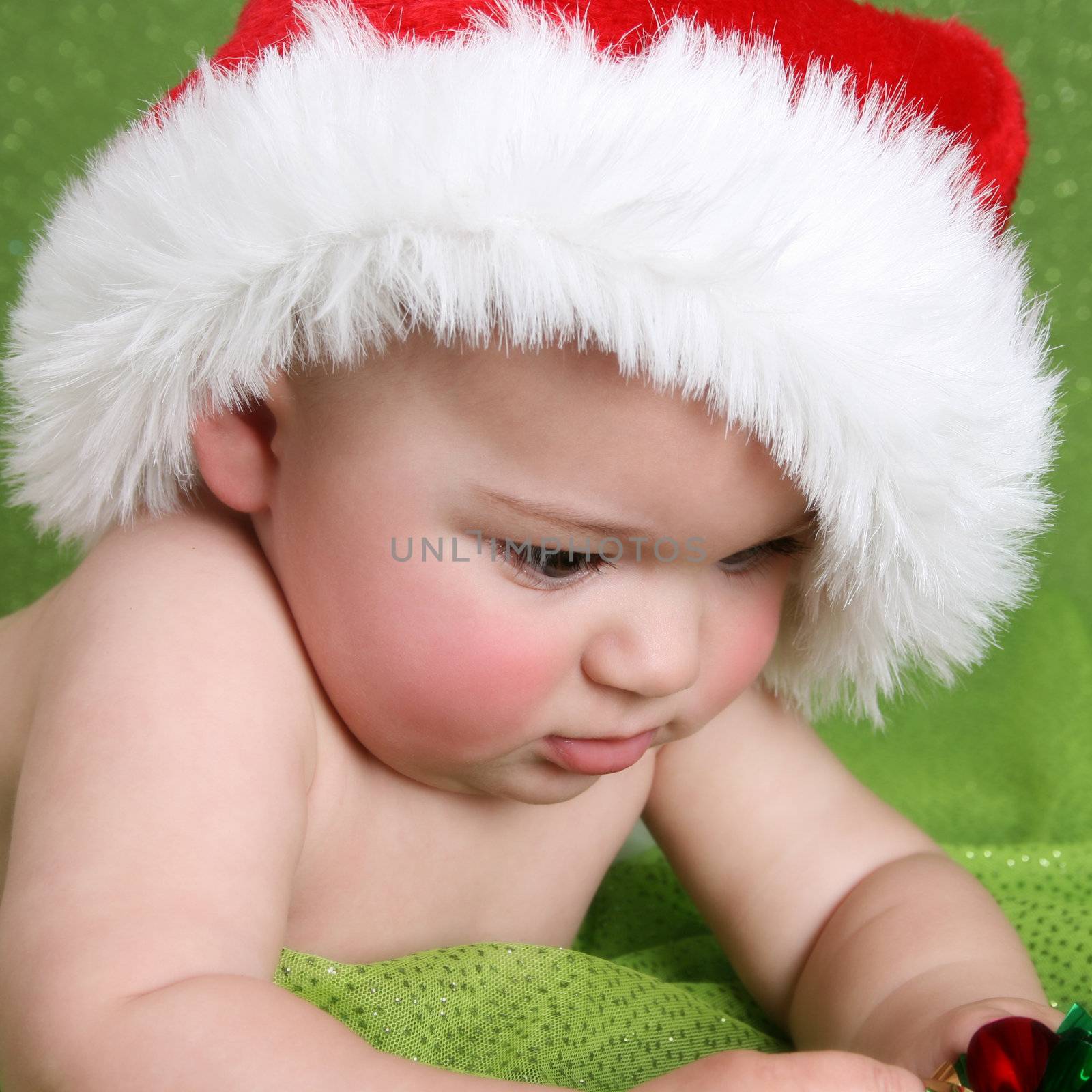 Christmas Baby playing with decorations on a green background