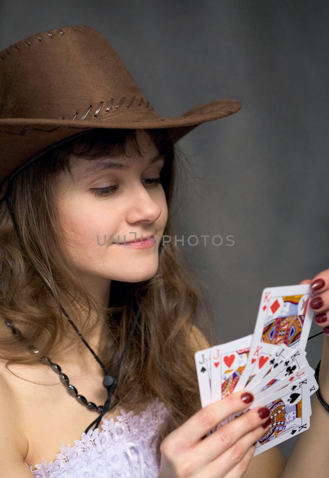 Cowgirl with a playing-cards in hand on black background