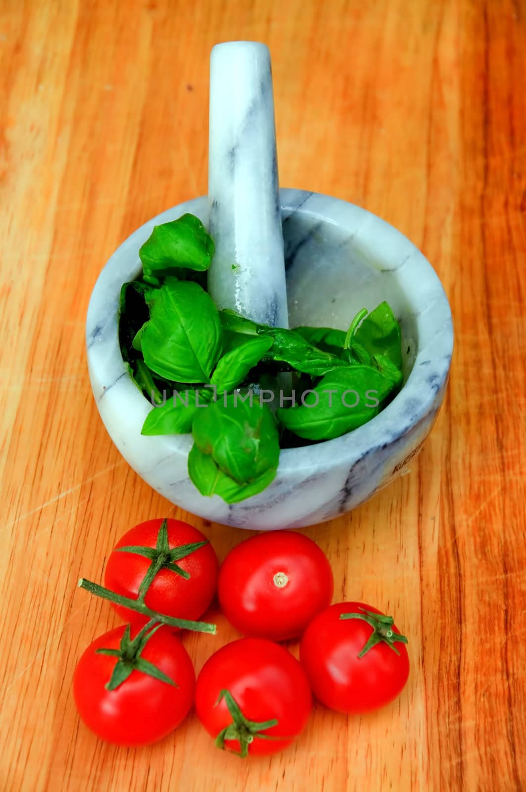 Tomatoes, basil and a mortar on a wooden cutting board