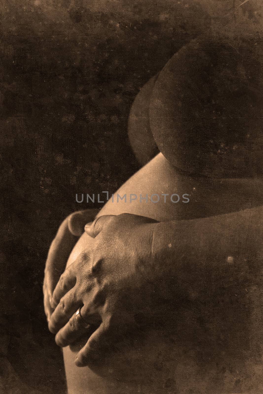 Two hands of a pregnant woman touching her skin retro