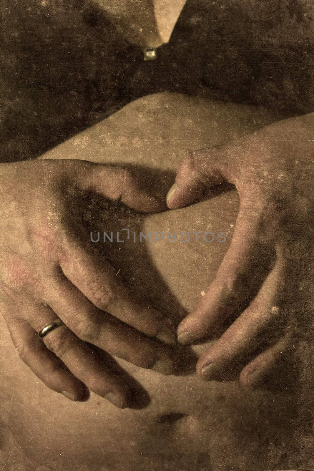 Two hands of a pregnant woman touching her skin retro