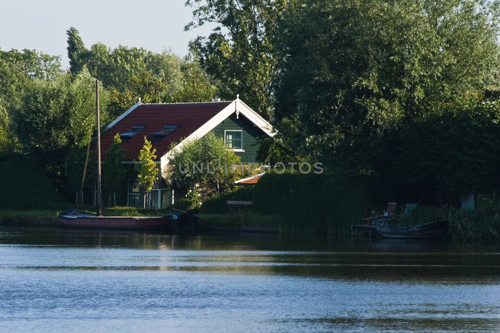 Small house in the country between trees at the waterside on a sunny morning in June