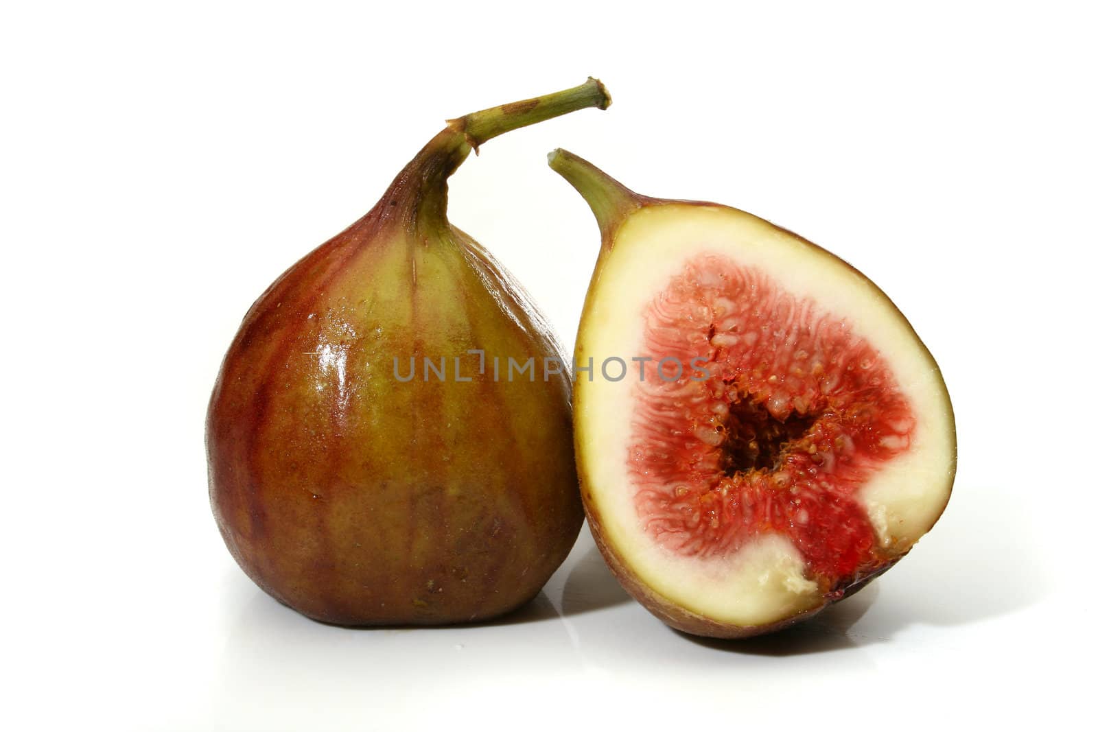 Two delicious figs, one sliced in half over a white background