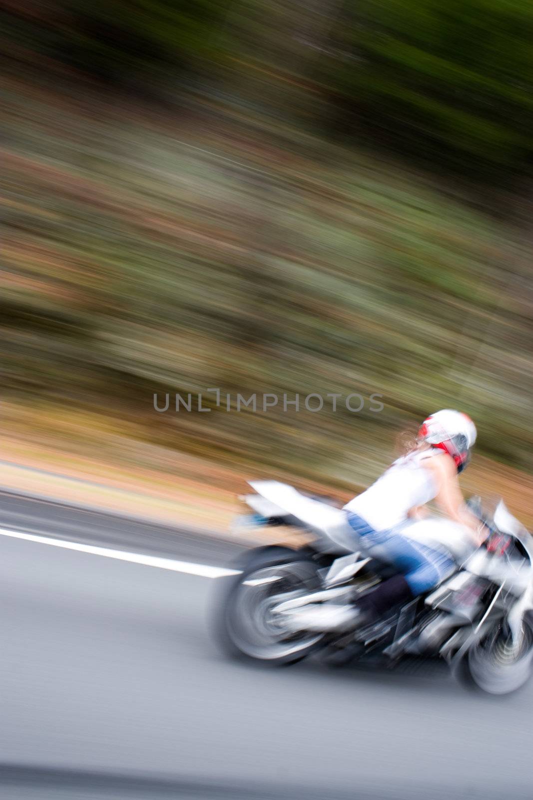 Abstract blur of a pretty girl driving a motorcycle at highway speeds.  Intentional motion blur.