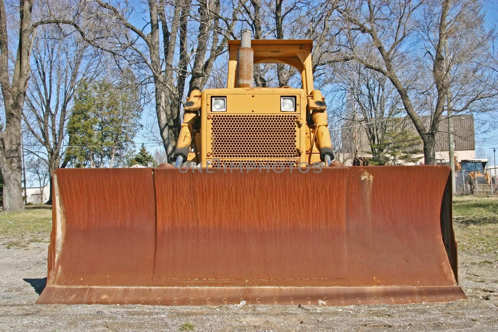 This is the front view of a well worn bulldozer. 