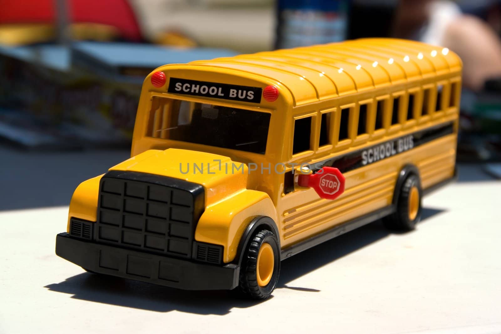 This is a picture of a toy school bus with the main focus on the front of the bus and stop sign.
